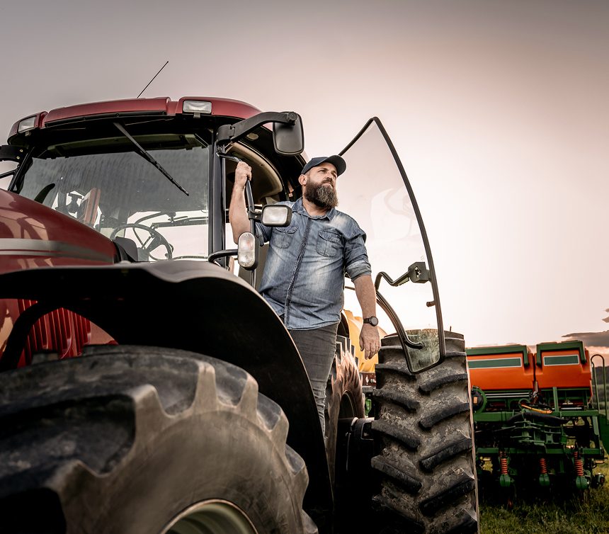 Farmer standing in doorway of red tractor.