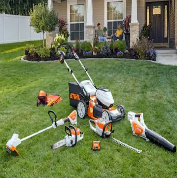 A set of orange and white garden power tools on a lawn.