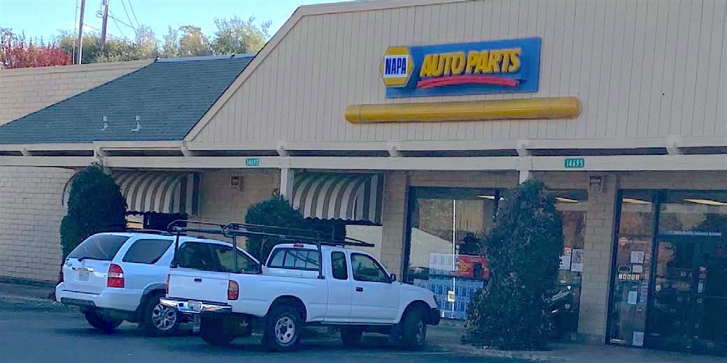 White pickup truck parked outside an auto parts store.