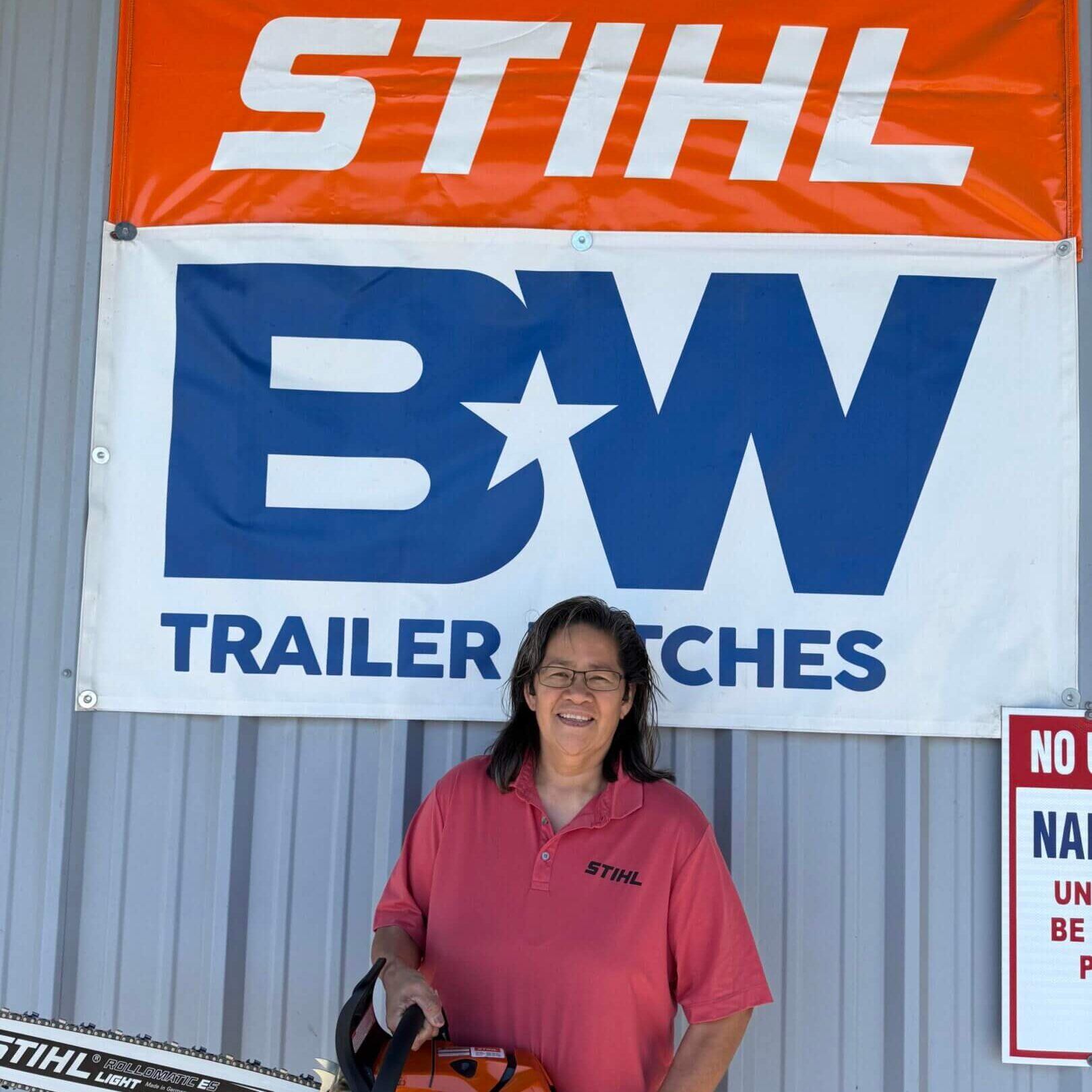 A woman standing in front of a BW Trailer Hitches sign.
